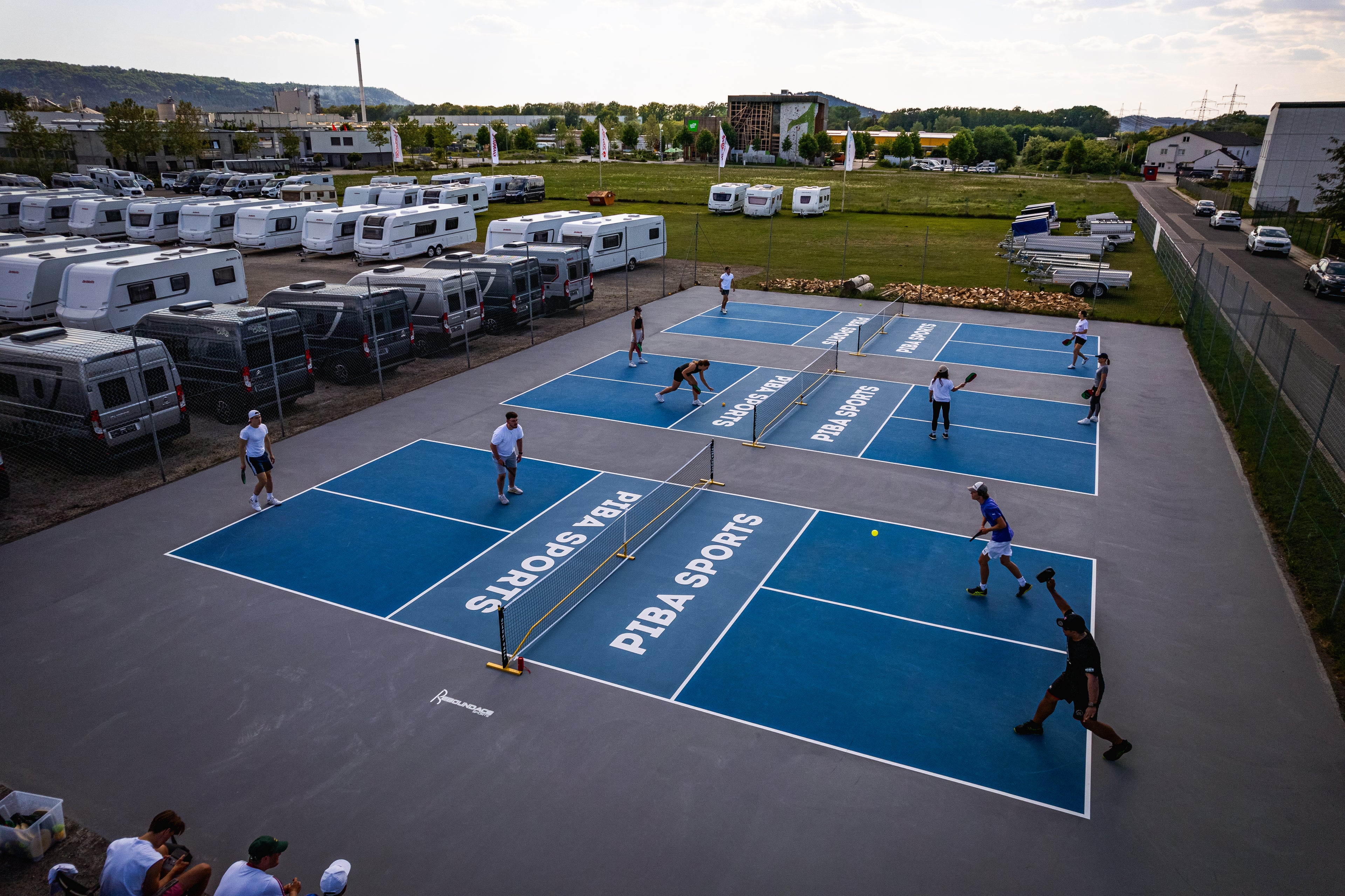Drohnenaufnahme der Outdoor Pickleball Courts von Piba Sports in Neumarkt in der Oberpfalz, auf denen zehn Spieler aktiv Pickleball spielen